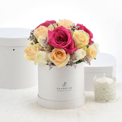 Vibrant pink and yellow roses in white box, accented with lavender sprigs.