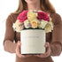 Vibrant pink, cream, yellow roses in elegant white "You Complete Me" gift box, held gently.