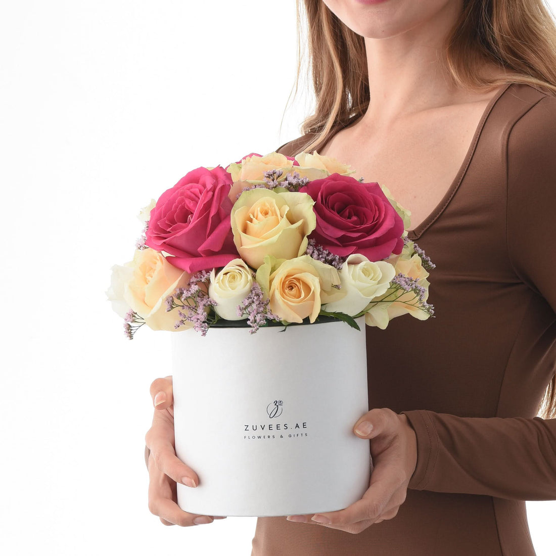 White box holds vibrant pink, yellow, and white roses with purple filler flowers.