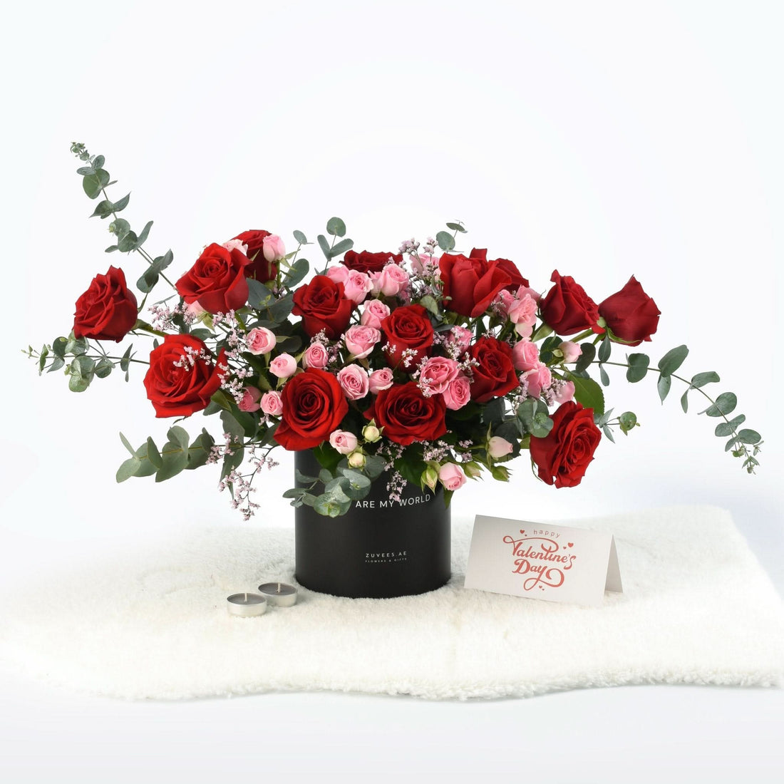 Bold red and pink roses in black cylinder vase with Valentine’s card.