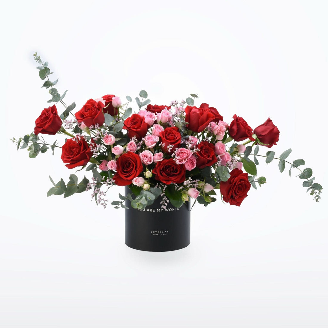 Bold red and pink roses with eucalyptus in sleek black vase.