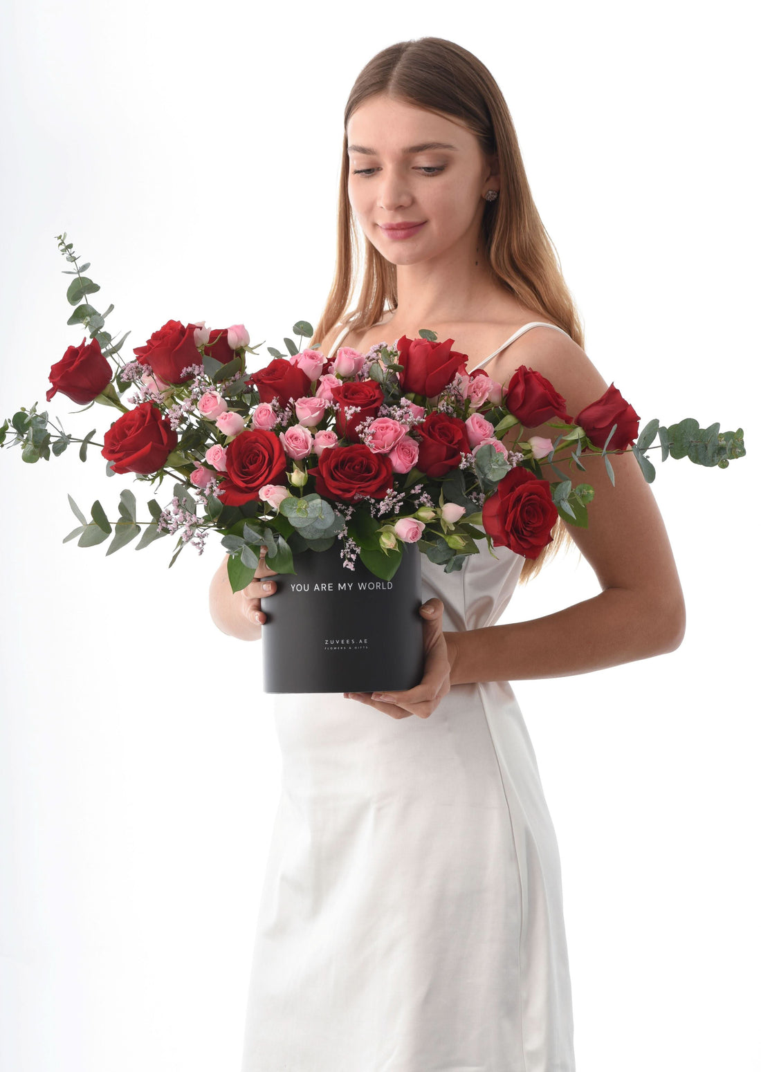 Woman holds black "You Are My World" box with red, pink roses, eucalyptus, baby&