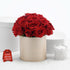 Vibrant red roses in beige box, beside "I love you" sign and lace candle.