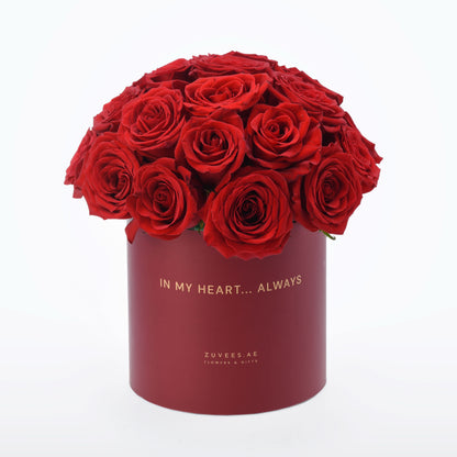 Vibrant red roses in matte burgundy cylinder box with gold "In My Heart... Always" text.