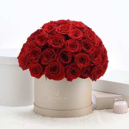 Luxurious red roses in elegant beige hat box, styled with soft white accents.