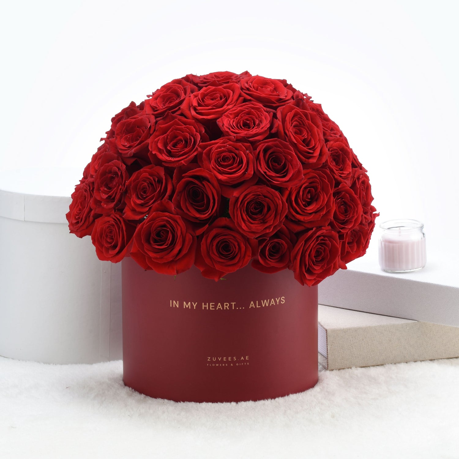 Vibrant red roses in matte burgundy box with gold "In My Heart... Always" inscription.