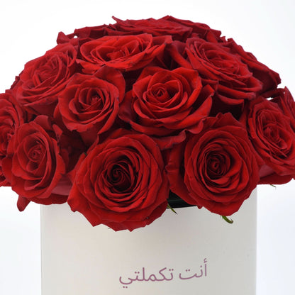 Vibrant red roses in white box with Arabic message.
