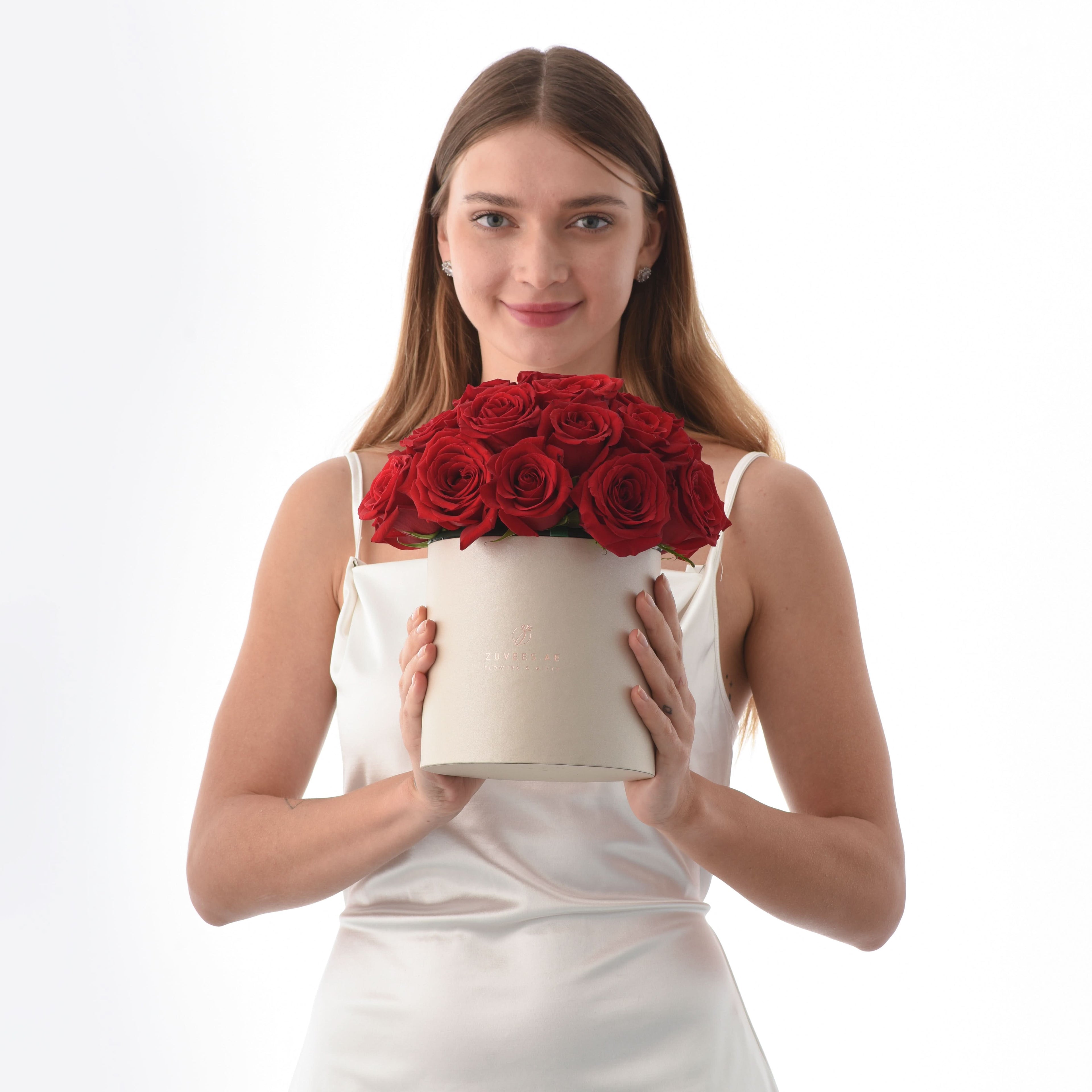 Woman holds luxurious cream box overflowing with vibrant red roses.