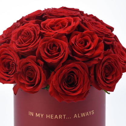 Vibrant red roses in deep burgundy box with gold "IN MY HEART... ALWAYS" inscription.