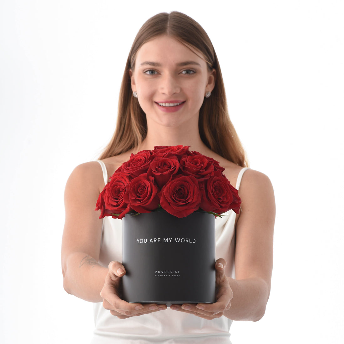 Woman holds black box of vibrant red roses with "You Are My World" message.