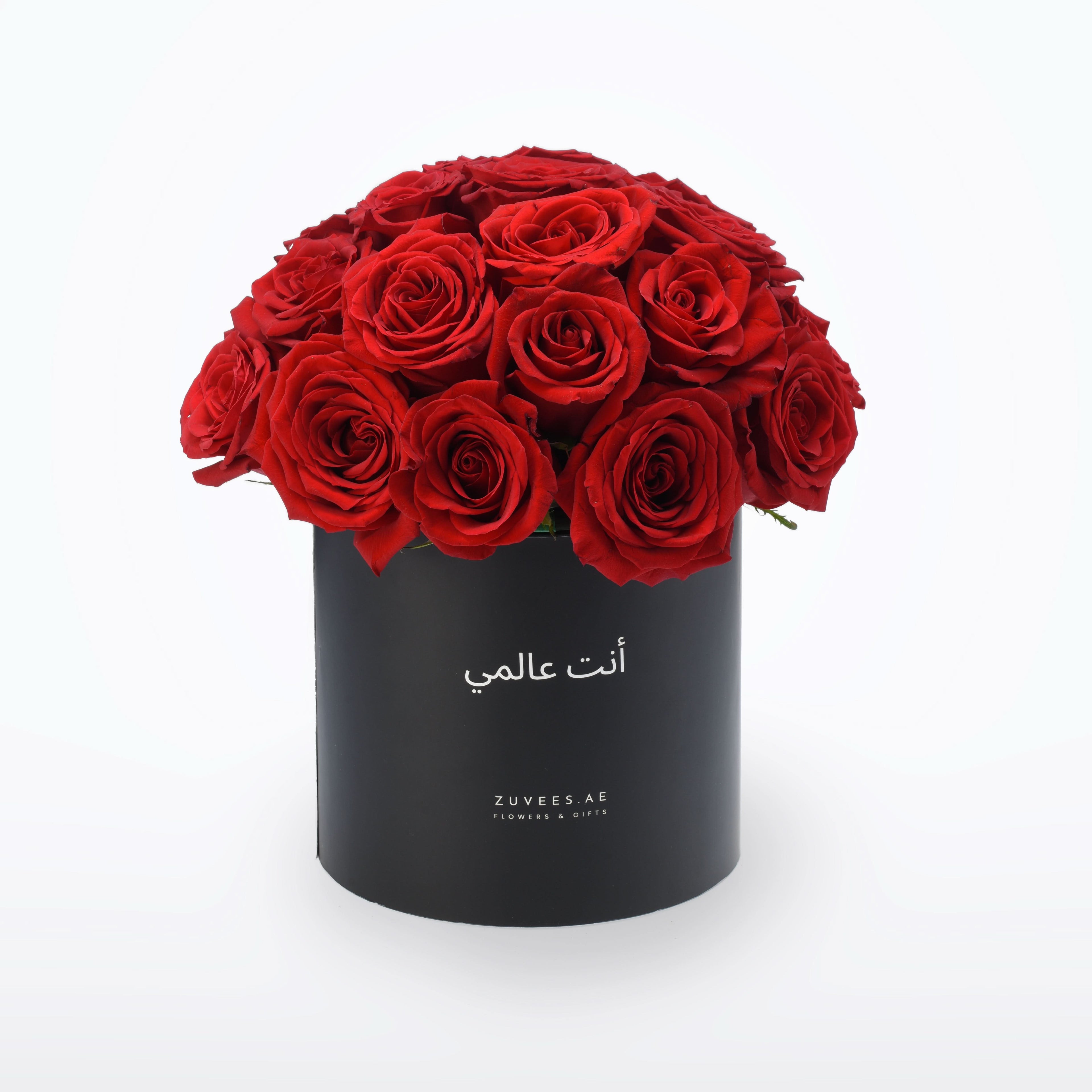 Vibrant red roses in sleek black box with Arabic inscription.