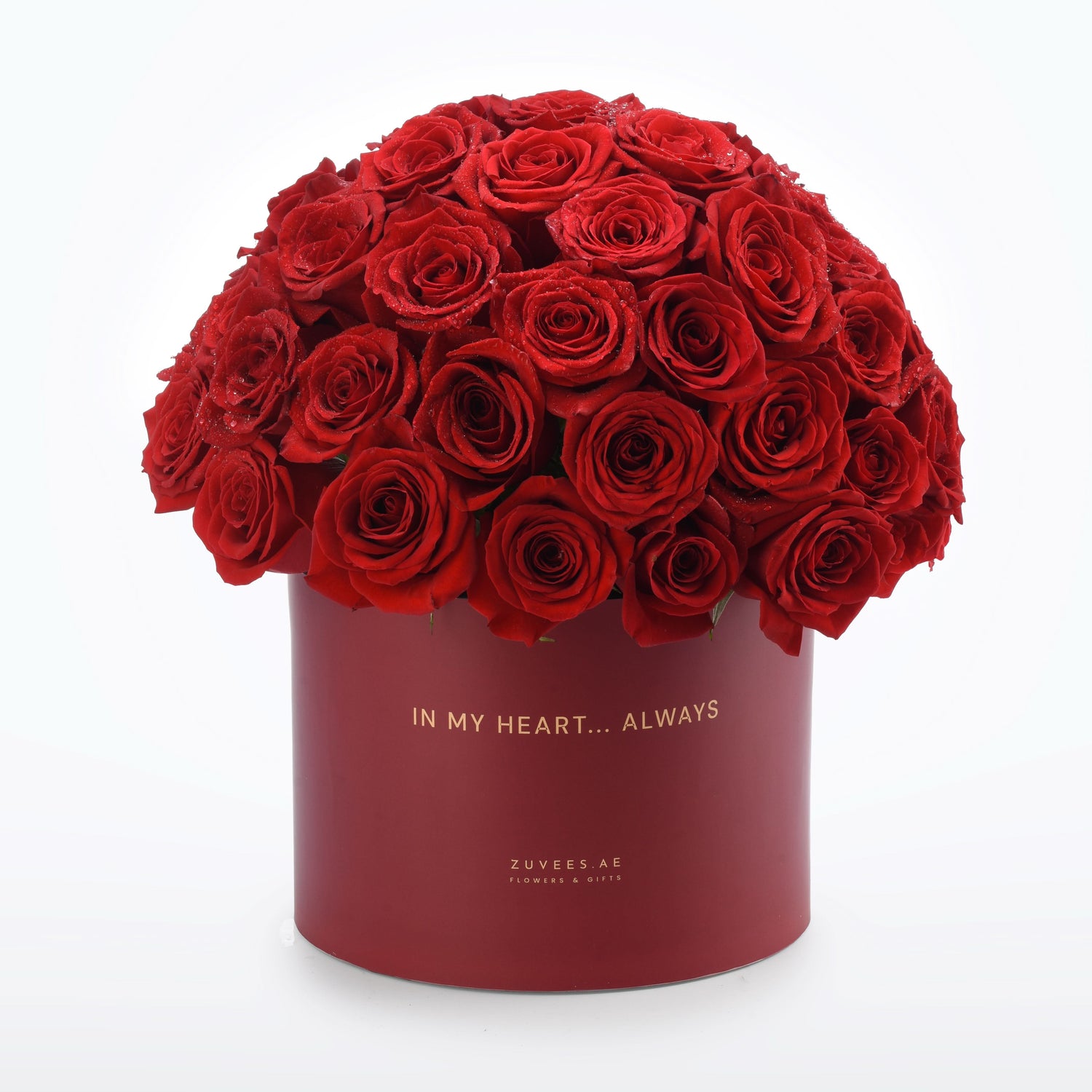 Luxurious red roses in deep burgundy box, gold text "IN MY HEART... ALWAYS", dew-kissed petals.