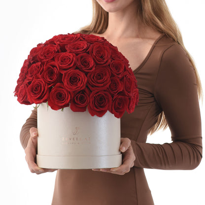 Woman holds luxurious white box overflowing with vibrant red roses.