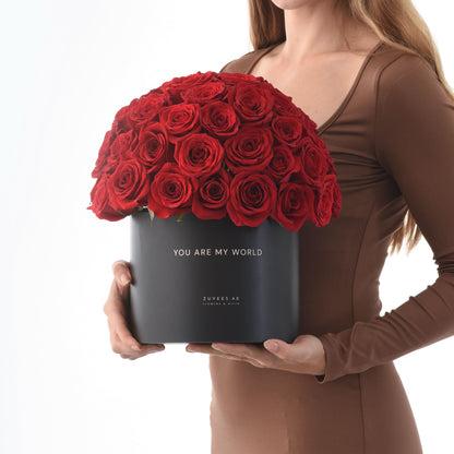 Vibrant red roses in matte black box reading "You Are My World".
