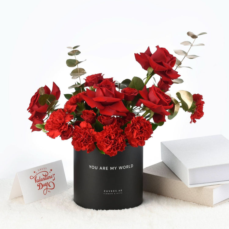 Vibrant red roses and carnations in black box with "You Are My World" text.