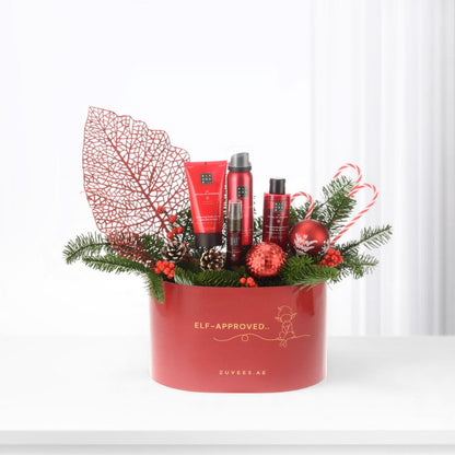 Vibrant red holiday gift basket with festive decor and Rituals skincare.