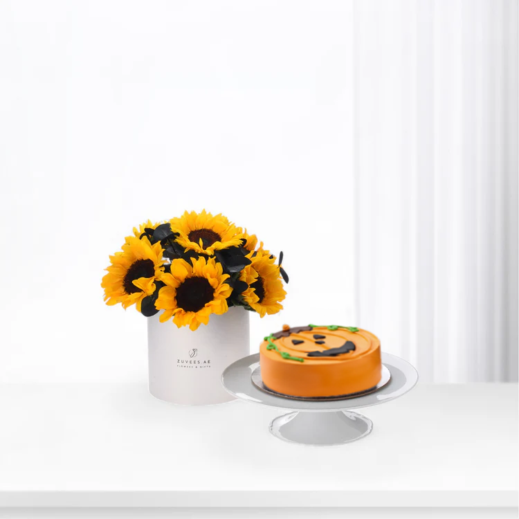 Vibrant sunflowers in white vase beside orange jack-o&