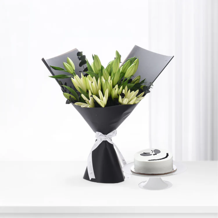 Elegant white lilies in black wrap with ribbon, beside minimalist white cake on stand.