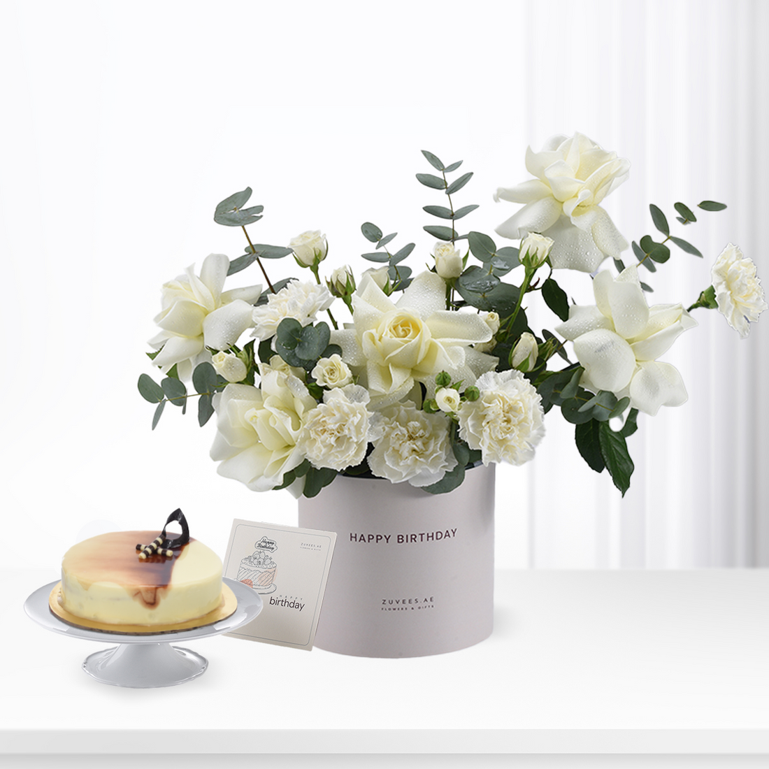 White roses and eucalyptus in "Happy Birthday" box with cheesecake.