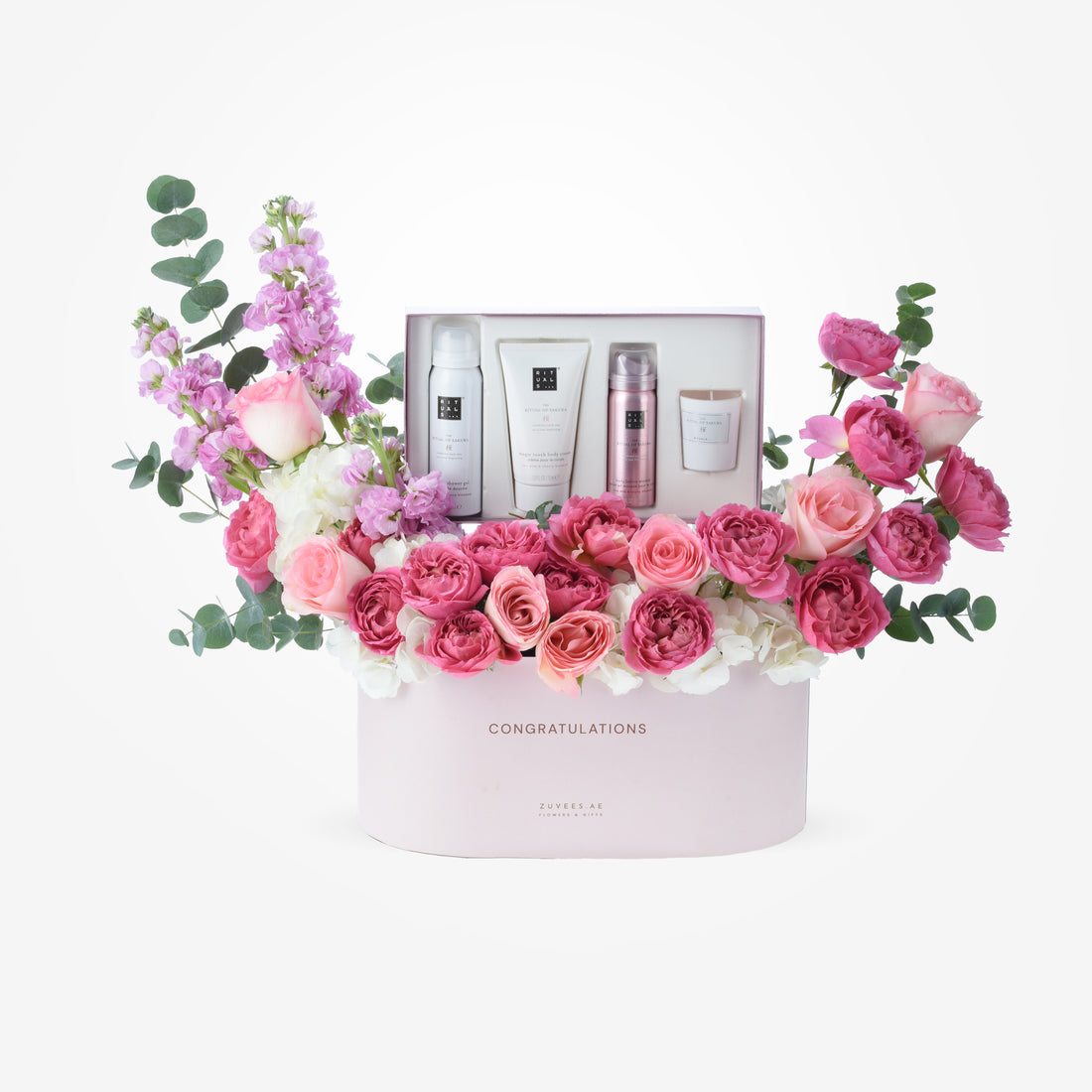 Pink floral arrangement with Rituals spa gifts in celebratory box.