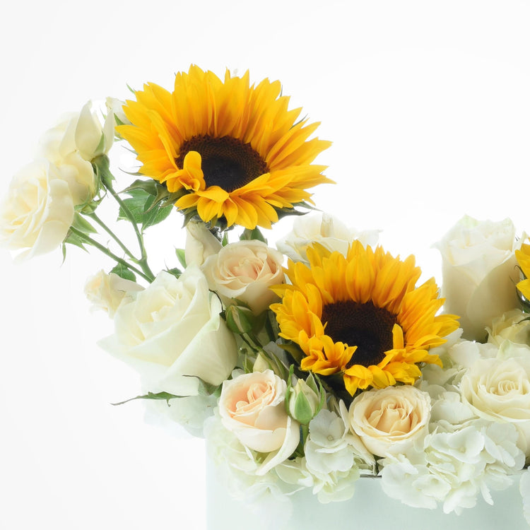 Vibrant yellow sunflowers and creamy white roses in minimalist floral arrangement.