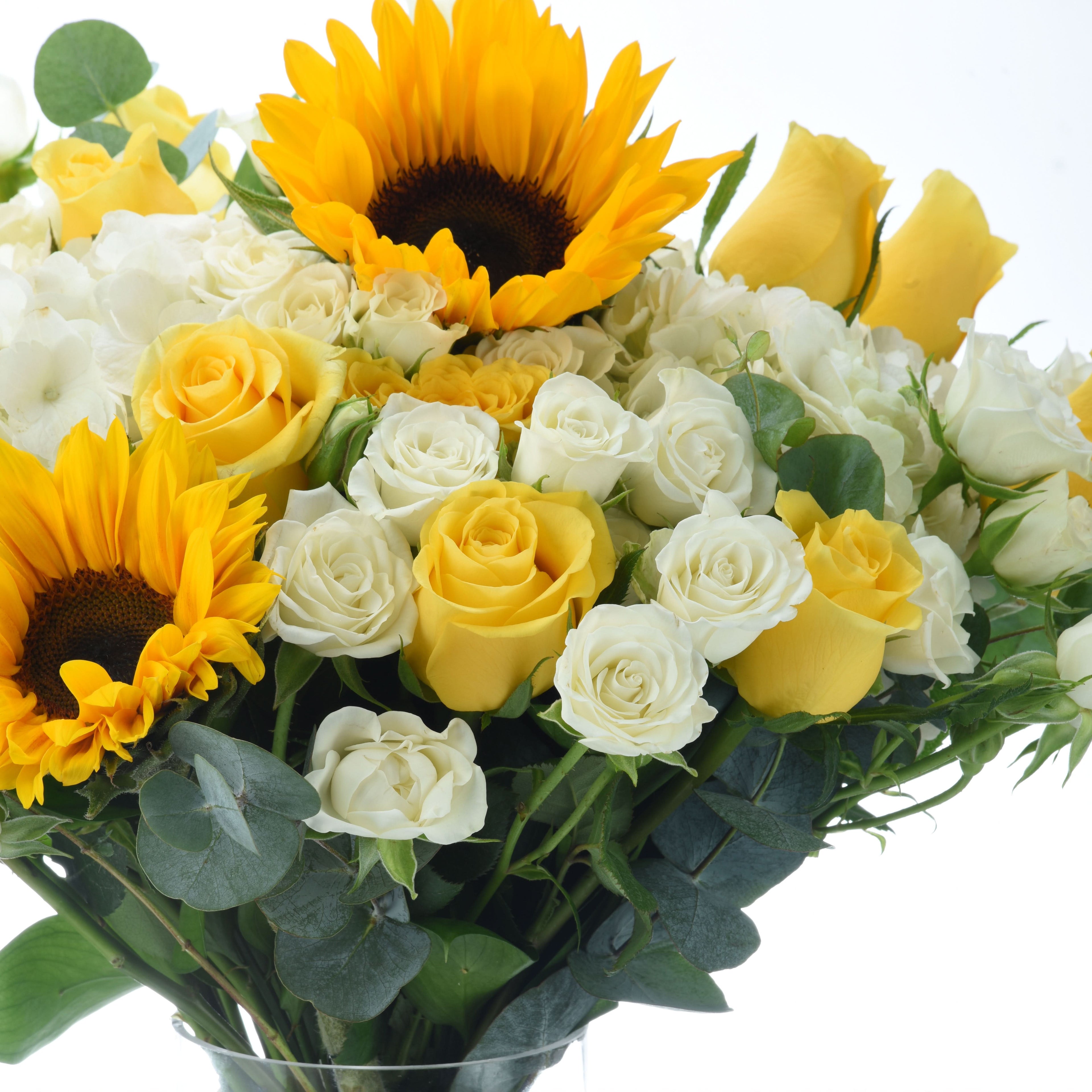 Vibrant yellow sunflowers and roses with white blooms and green eucalyptus.