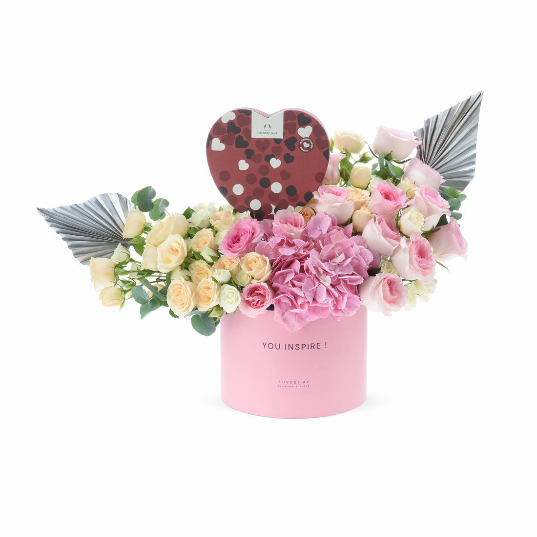 Pink floral arrangement with angel wings and heart-shaped chocolate box.