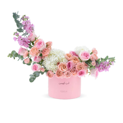 Soft pink roses, hydrangeas, and eucalyptus in elegant pastel pink cylindrical box.