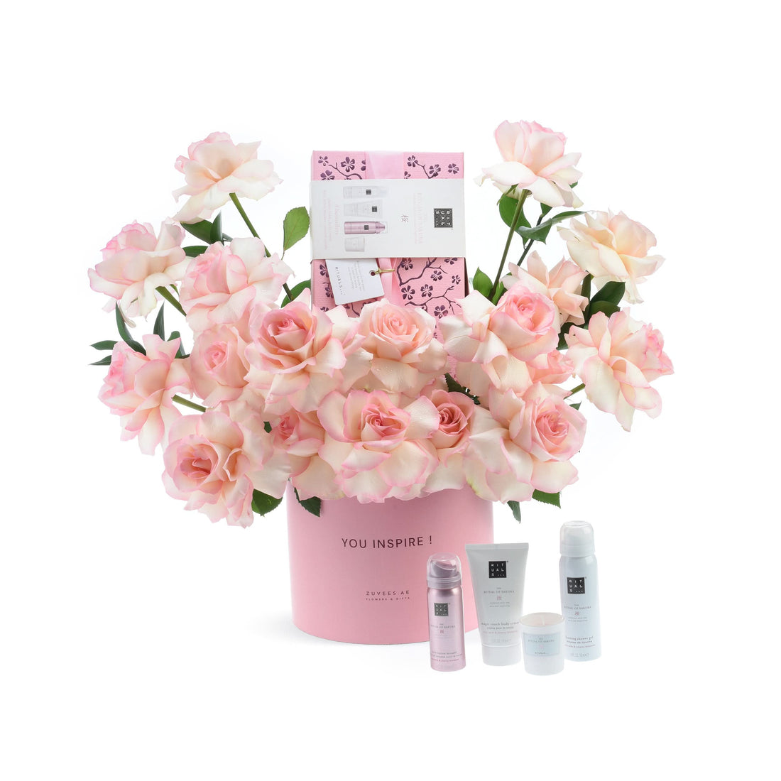 Soft pink roses bloom around a branded pink vase and luxury skincare set.