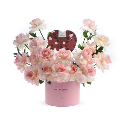 Pink roses in a "YOU INSPIRE!" box with heart-shaped chocolate gift, elegant and romantic.
