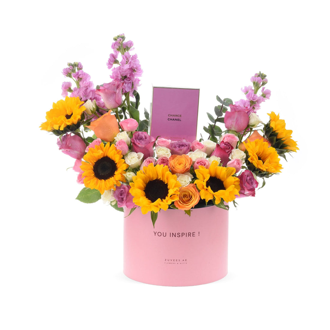 Vibrant sunflowers, pink roses, and purple blooms in pink "YOU INSPIRE!" box with Chanel perfume.