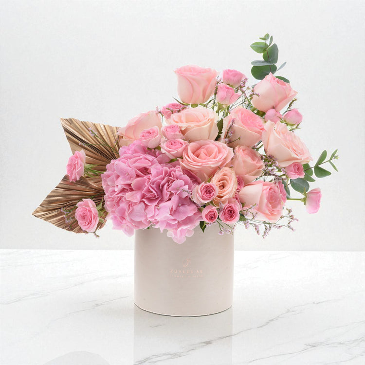 Elegant pink rose and hydrangea bouquet in branded beige box with gold leaf accent.