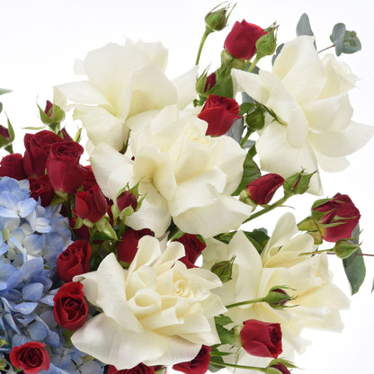 White and red roses with blue hydrangeas, dewdrops, fresh greenery.