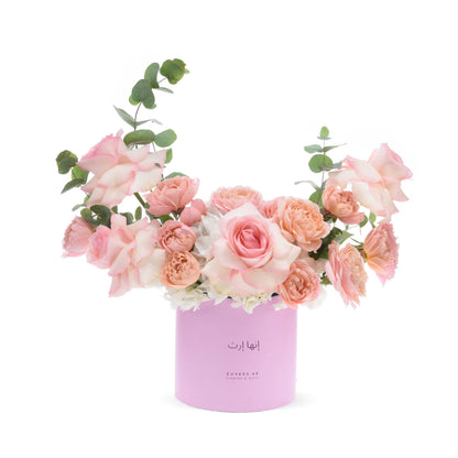 Soft pink roses and eucalyptus in pastel pink cylinder vase.