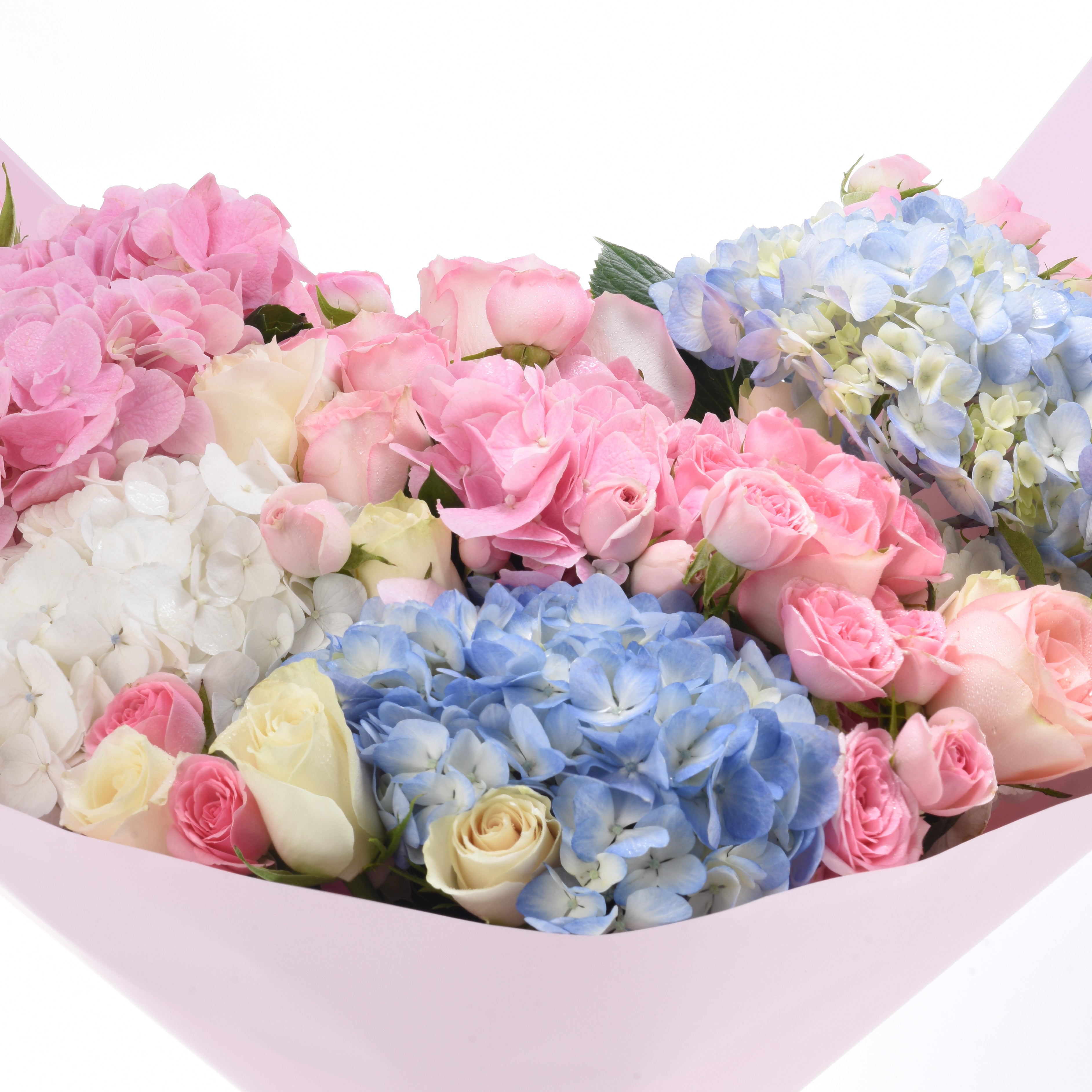 Pastel pink, blue, and white hydrangeas and roses in soft pink box.