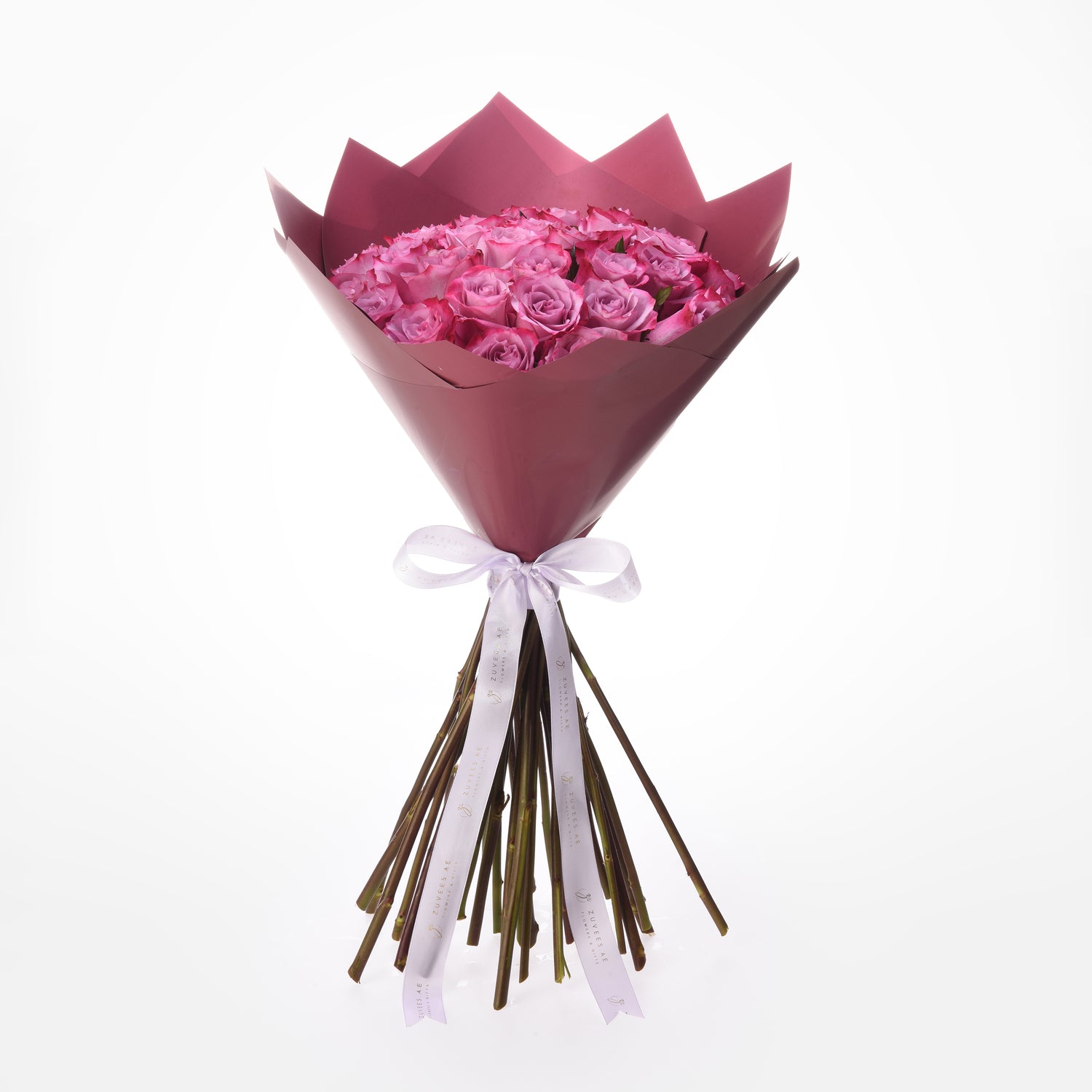 Pink roses in dusky pink wrap, tied with branded white ribbon, elegant gift bouquet.