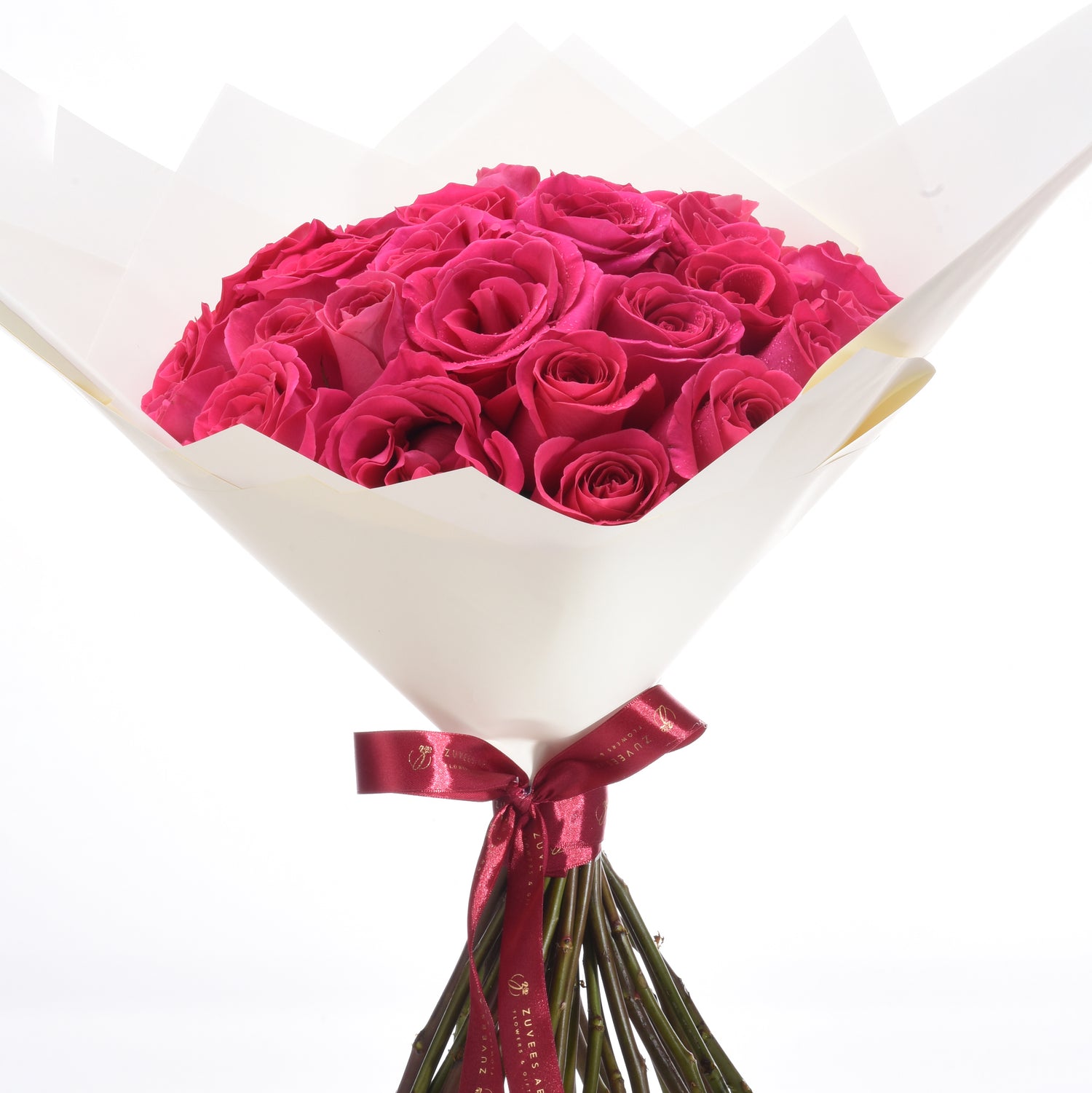 Vibrant fuchsia roses in crisp white paper, tied with burgundy satin ribbon.