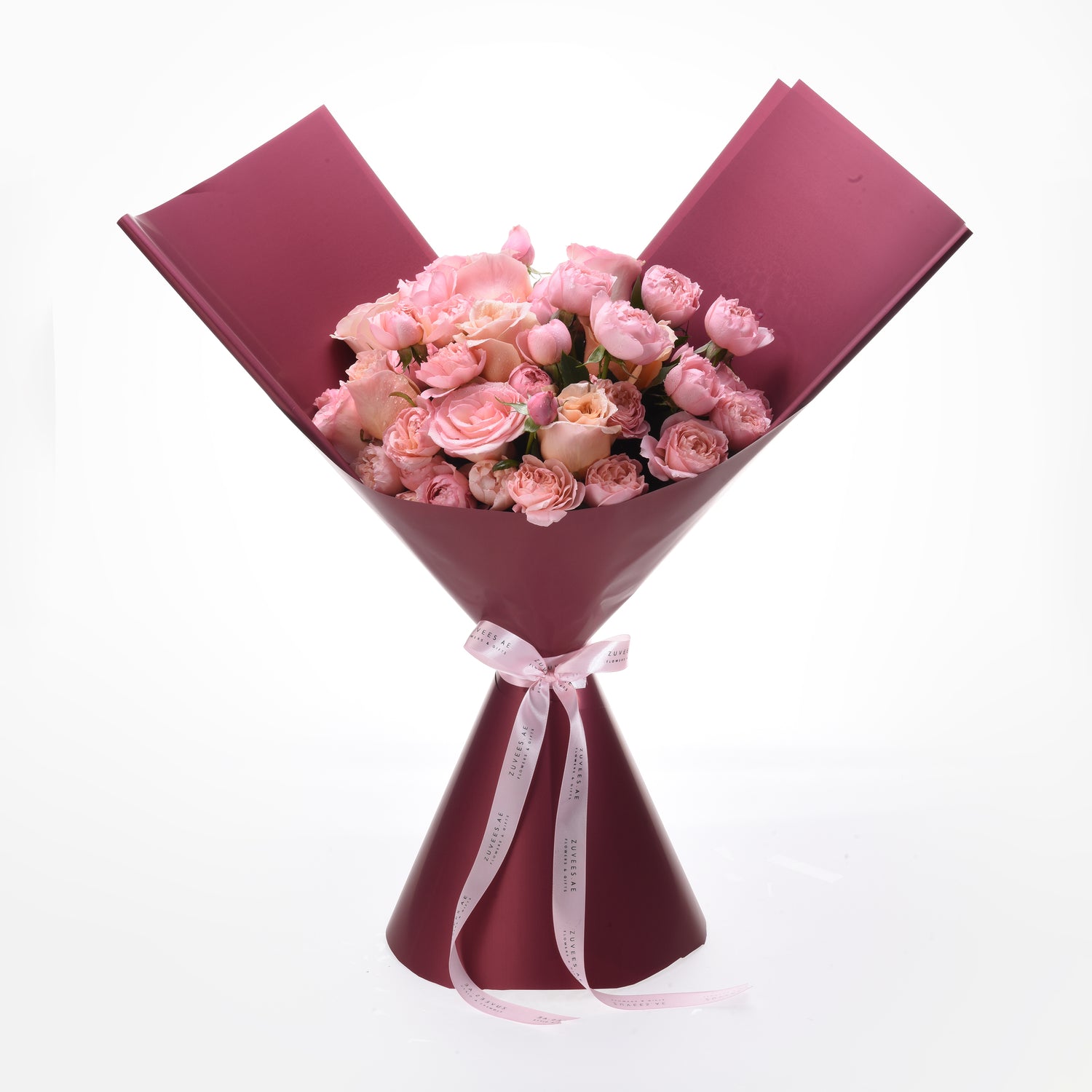 Pink roses in deep burgundy wrap, tied with branded ribbon, elegant gift bouquet.
