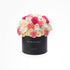 Black box holds vibrant pink, peach, and white roses and carnations.