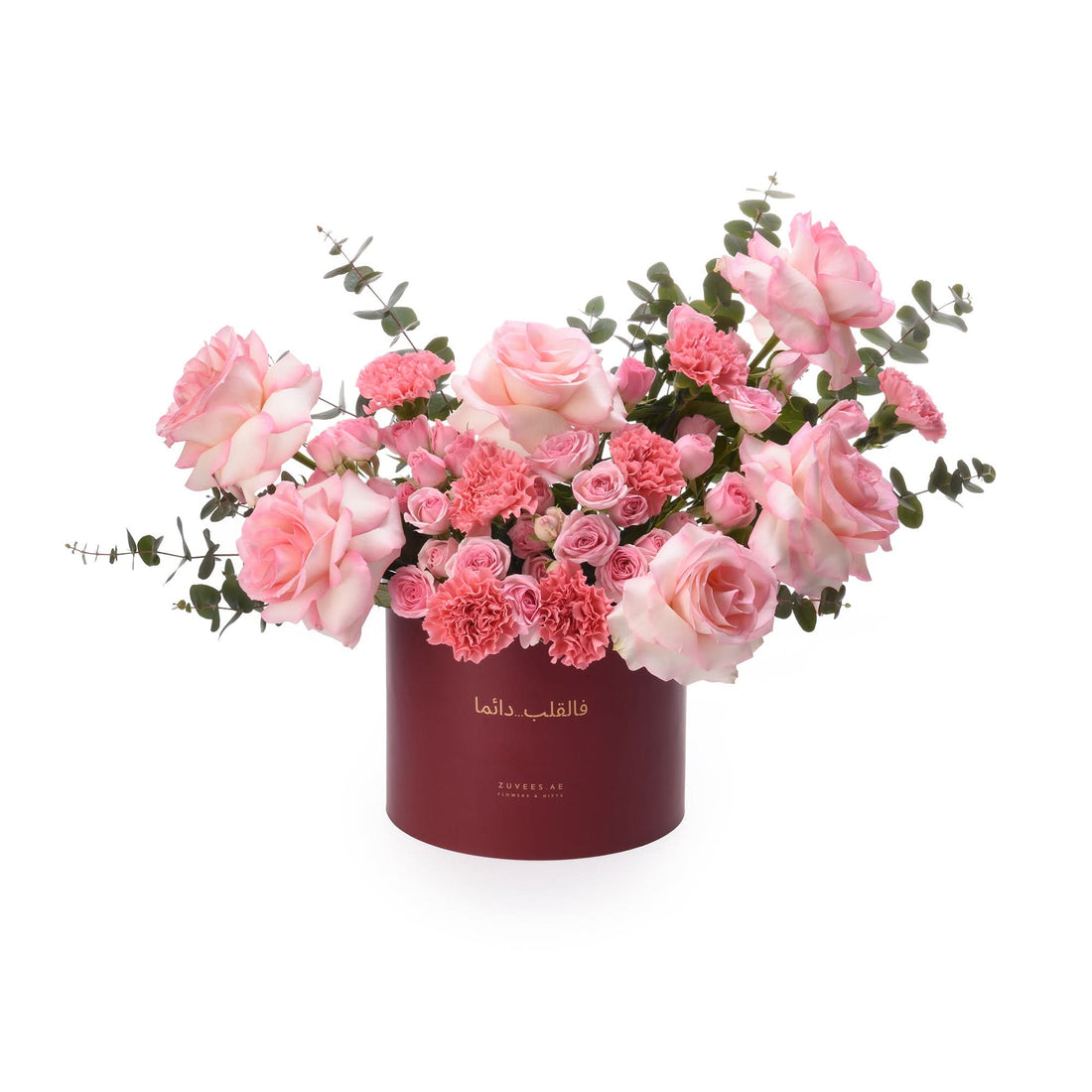 Elegant pink roses and carnations in deep red cylindrical box with Arabic script.