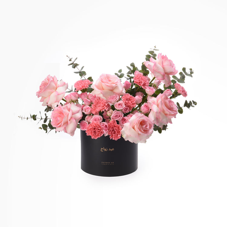 Elegant pink roses and carnations in sleek black box with gold text.