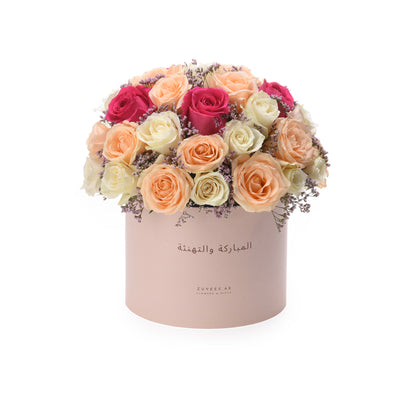 Pastel pink box holds vibrant roses and lavender, with Arabic "Congratulations" greeting.