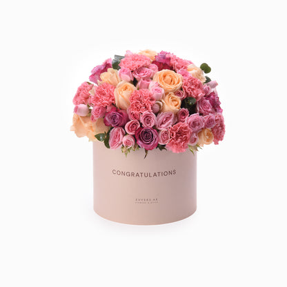 Pastel pink box overflowing with vibrant roses and carnations, "Congratulations" printed.