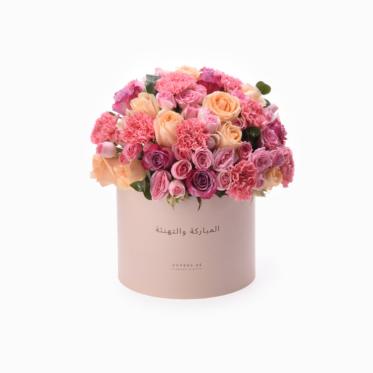 Pink and peach roses and carnations in matte blush box with Arabic “Congratulations” text.