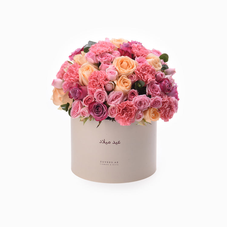 Pink and peach roses, carnations in cream box with Arabic script.