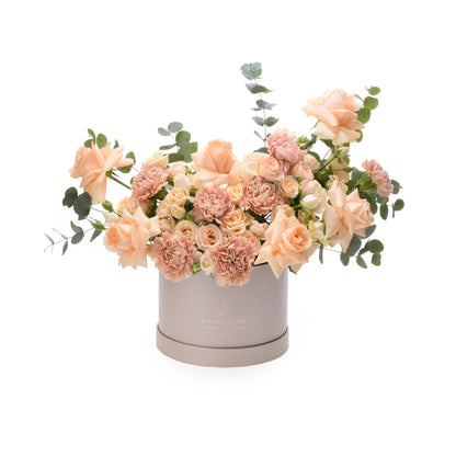 Soft peach roses and carnations in elegant grey box with eucalyptus.