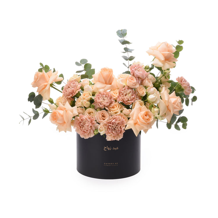 Elegant peach roses and carnations in sleek black box with gold script.