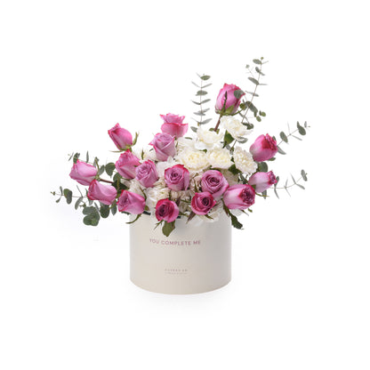 Pink roses and white blooms in a white box reading "You Complete Me".