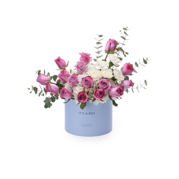 Pastel blue box holds vibrant pink roses and white blooms, accented with eucalyptus.
