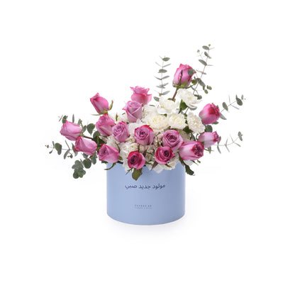 Light blue box holds pink roses and white blooms with eucalyptus.